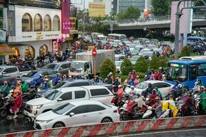 ho Chi Minh, viet nam - - 24 April 2023 Vietnamesisch Menschen tragen Helm und Regenjacke Reiten Motorrad im schwer Regen und der Verkehr Marmelade. foto