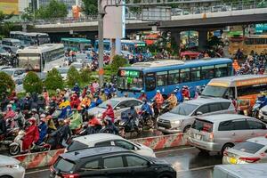 ho Chi Minh, viet nam - - 24 April 2023 Vietnamesisch Menschen tragen Helm und Regenjacke Reiten Motorrad im schwer Regen und der Verkehr Marmelade. foto