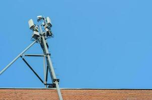 Mobilfunkantenne auf dem Dach eines Backsteinhauses auf blauem Himmelshintergrund. foto