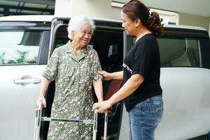 pflegekraft hilft asiatischen älteren frauen mit behinderungspatienten, in ihr auto zu steigen, medizinisches konzept. foto
