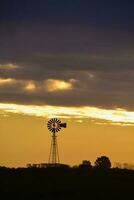 Landschaft mit Windmühle beim Sonnenuntergang, Pampas, Patagonien, Argentinien foto