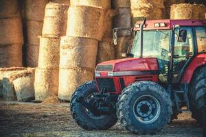 Bauernhof Traktor im Vorderseite von Heu Ballen. foto