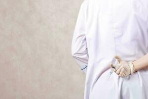 ein Arzt gekleidet im ein Fachmann Uniform versteckt sich Spritze mit Medikation foto