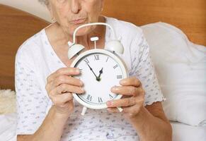 alt Frau mit Jahrgang Alarm Uhr foto