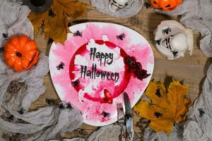 glücklich Halloween. schmutzig rot blutig Teller mit Silber Besteck auf Halloween Tisch. , Teller foto