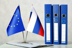 zwei Flaggen von das EU und Russland auf ein Weiß Tisch. Nahansicht foto