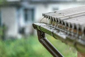 Regen fließt Nieder von ein Dach runter, Sommer- Wetter foto