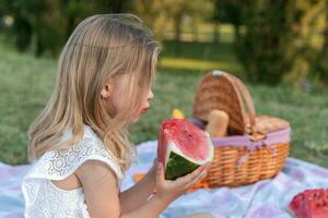 Porträt von ziemlich wenig Mädchen ist haben Spaß während Essen ein Scheibe von Wassermelone foto
