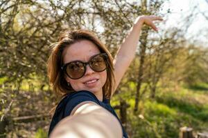 schön Frau nehmen Selfie draußen während ein glücklich gehen im das Landschaft foto