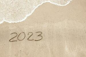 Inschrift auf das Strand Sprichwort 2023 mit ein Welle foto