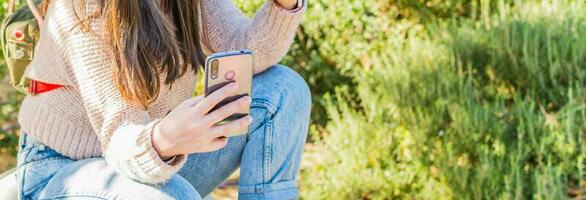 Frau Hand halten ein Zelle Telefon, im ein Park, auf ein sonnig Tag. foto