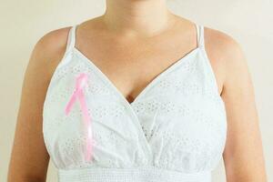 das Leistung zu Kampf Brust Krebs, Frau tragen Rosa Bänder zum Brust Krebs Kampagne auf Weiß Hintergrund foto