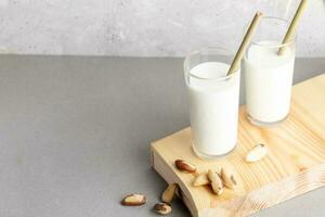 zwei Brille von vegan gemacht von Brasilien Nüsse Milch und Nüsse auf hölzern Tafel auf grau Hintergrund. Kopieren Raum. foto