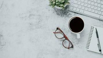 oben Sicht, modern Weiß Büro Schreibtisch mit Tastatur Computer, Tasse von Kaffee, Stift, Brille und Notizbuch, Kopieren Raum, spotten hoch. foto