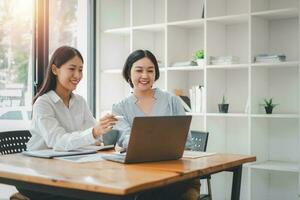 zwei Geschäftsfrau Arbeiten zusammen auf Laptop Computer. kreativ weiblich Führungskräfte Treffen im ein Büro mit Laptop pc und lächelnd. foto