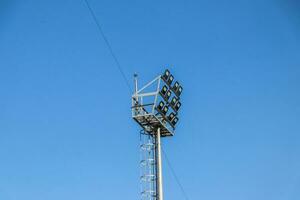 Silhouette von ein Scheinwerfer auf ein Blau Himmel Hintergrund. Lampen zum Stadion Beleuchtung. foto