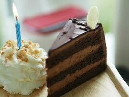 Geburtstag Kuchen Stück Schokolade Kuchen mit ausgepeitscht Sahne auf oben Mandel Kerze im hölzern Tablett foto