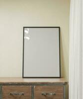 sauber minimalistisch Rahmen Attrappe, Lehrmodell, Simulation Poster auf das hölzern Tabelle und neben das Weiß Vorhang und Beige Mauer Farbe foto