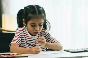 asiatisch wenig Mädchen Zeichnung mit Bleistifte beim heim. Bildung Konzept. foto