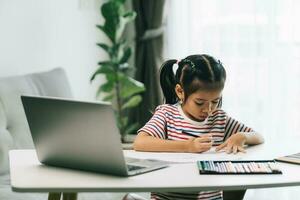 wenig asiatisch Mädchen mit Laptop Computer beim heim. Bildung und Technologie Konzept. foto