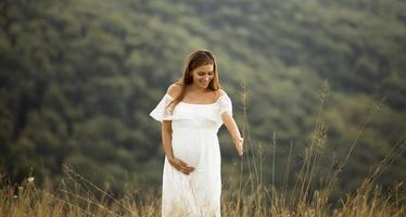 junge schwangere Frau auf dem Feld