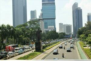 Jakarta, Indonesien-18 Juni 2023 Aussicht von sudirman Straße mit sudirman Statue im das Mitte foto