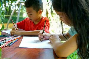 asiatisch Kinder sind glücklich zu zeichnen ihr Fantasien und Farbe mit Buntstifte im ihr schonen Zeit beim Zuhause während Schule Feiertage. Sanft und selektiv Fokus. foto