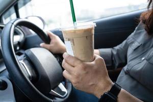 Asiatische Dame hält Eiskaffee im Auto gefährlich und riskiert einen Unfall.