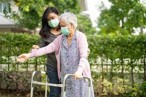 Asiatische Seniorin oder ältere alte Dame, die eine Gesichtsmaske trägt, die im Park neu ist, um die Sicherheitsinfektion des Covid-19-Coronavirus zu schützen. foto