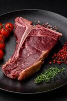 roh saftig Rindfleisch T-Bone Steak mit Salz, Gewürze und Kräuter foto