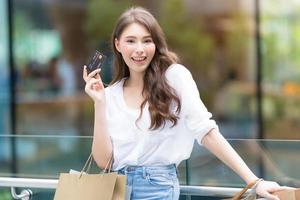 Black Friday Konzept, Frau hält viele Einkaufstüten mit Kreditkarte und lächelt foto
