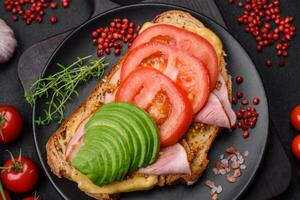 köstlich nahrhaft gegrillt Toast mit Schinken, Käse, Tomaten und Avocado foto