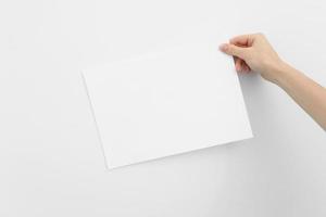 Frauenhand, die das Papier auf weißem Hintergrund hält. Platz für Text. leeres Stück Beschriftungspapier foto