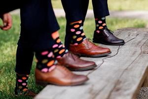 stylische Herrensocken. stylischer Koffer, Herrenbeine, bunte Socken und neue Schuhe. Konzept von Stil, Mode, Schönheit und Urlaub foto