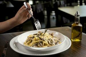 Essen luxuriös cremig Pilz Fettuccine, Innerhalb ein Restaurant - - jung Frau Hand foto