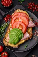 köstlich nahrhaft gegrillt Toast mit Schinken, Käse, Tomaten und Avocado foto