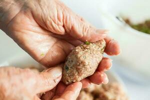 Schritt durch Schritt Levantiner Küche kibbeh Vorbereitung. schließen oben von ein Senior Frau Hände Gestaltung ein kibbeh foto