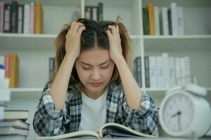 asiatische studentin hat angst wegen prüfungen, frauen bereiten sich auf prüfungen vor und lernen unterricht in der bibliothek. Stress, Verzweiflung, Eile, Missverständnisse beim Lesen, Entmutigung, Erwartung, Wissen foto