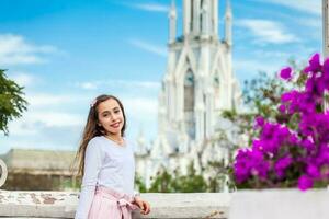 schön jung Mädchen auf das Ortiz Brücke mit das berühmt gotisch Kirche von la Ermita im das Stadt von cali im Kolumbien foto