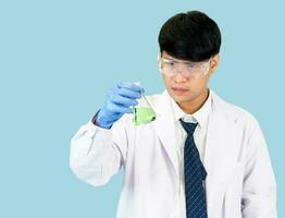 asiatisch Mann Schüler Wissenschaftler im Reagens Mischen Labor im ein Wissenschaft Forschung Labor mit Prüfung Röhren von verschiedene Größen. auf das Fußboden im Labor Chemie Labor Blau Hintergrund. foto