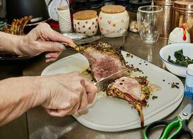 Koch schneidet Lamm Rippen mit Knoblauch und Senf Soße, nach Backen im das Ofen foto