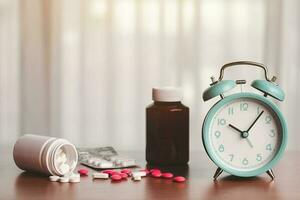 ein Alarm Uhr mit ein Stapel von Tabletten und Medizin Flaschen auf ein hölzern Tabelle foto