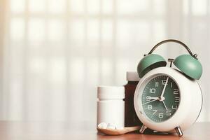 ein Alarm Uhr mit Tabletten auf das hölzern Löffel und Medizin Flaschen auf das Tabelle foto