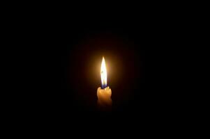 ein Single Verbrennung Kerze Flamme oder Licht glühend auf ein Weiß Spiral- Kerze auf schwarz oder dunkel Hintergrund auf Tabelle im Kirche zum Weihnachten, Beerdigung oder Denkmal Bedienung mit Kopieren Raum. foto