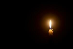 ein Single Verbrennung Kerze Flamme oder Licht glühend auf ein Weiß Spiral- Kerze auf schwarz oder dunkel Hintergrund auf Tabelle im Kirche zum Weihnachten, Beerdigung oder Denkmal Bedienung mit Kopieren Raum. foto