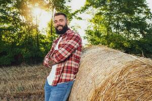 Farmer ist Stehen neben Ballen von Heu. er ist zufrieden nach erfolgreich Ernte. foto