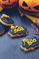 Halloween-Lebkuchenplätzchen auf dunklem Hintergrund, mit Halloween-Minikürbissen und Dekoration foto