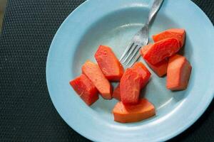 Nahansicht von frisch rot Papaya Obst auf ein Teller mit ein Gabel foto