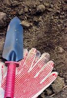 Schutzhandschuhe und kleine Kelle auf dem Boden, Gartenkonzept foto