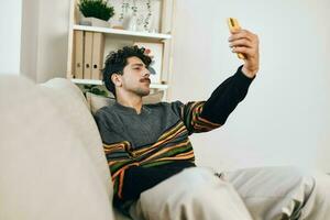 Selfie Mann Zuhause Botschaft Tippen Sofa Telefon Freizeit Technologie Geschäft mit Lebensstil Kommunikation foto